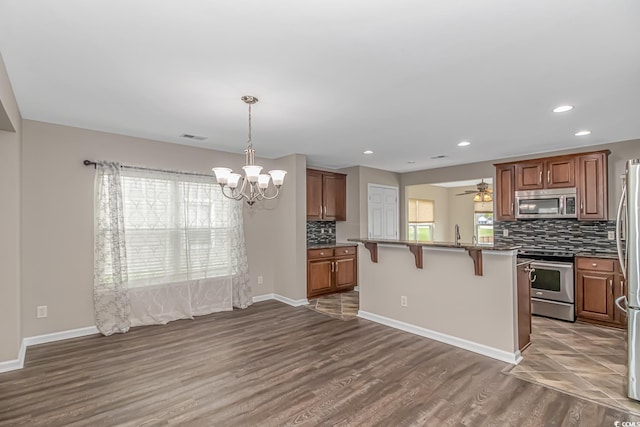 kitchen featuring a breakfast bar, plenty of natural light, stainless steel appliances, and dark wood-type flooring