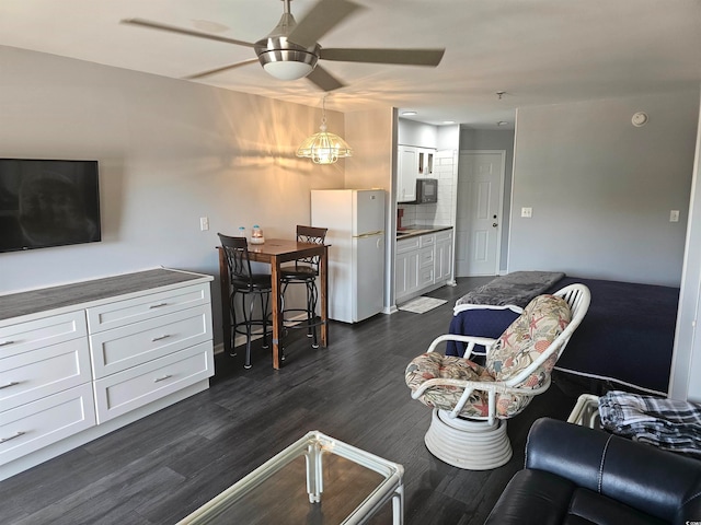 living room with ceiling fan with notable chandelier and dark wood-type flooring