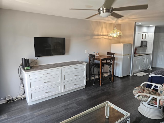 living room with ceiling fan with notable chandelier and dark hardwood / wood-style flooring