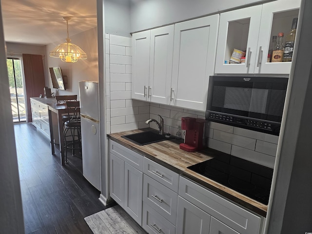 kitchen with a notable chandelier, white cabinets, decorative backsplash, decorative light fixtures, and dark hardwood / wood-style flooring