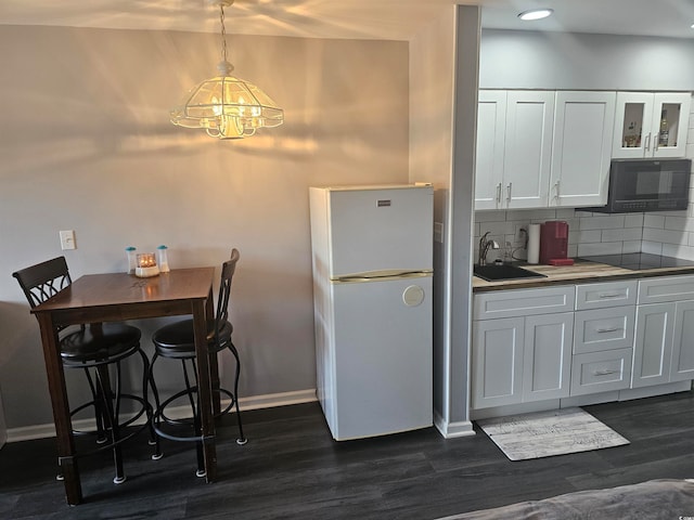 kitchen with white cabinetry, backsplash, pendant lighting, black appliances, and a notable chandelier