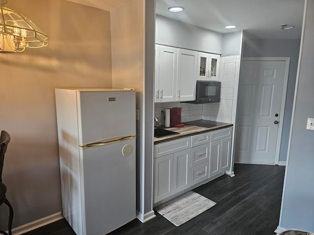 kitchen featuring hanging light fixtures, white cabinetry, dark wood-type flooring, tasteful backsplash, and white fridge