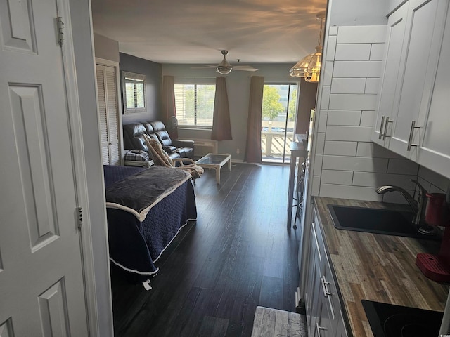 interior space with dark hardwood / wood-style flooring, ceiling fan with notable chandelier, and sink