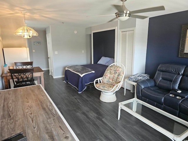 living room featuring ceiling fan with notable chandelier and dark hardwood / wood-style flooring