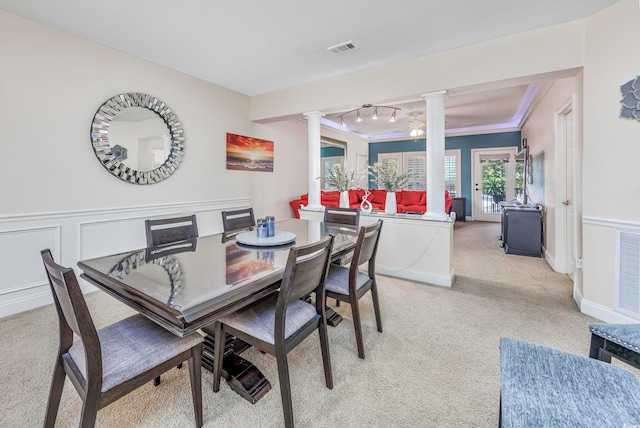 carpeted dining area with crown molding and ornate columns