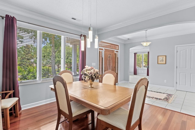 dining area featuring a textured ceiling, crown molding, and light hardwood / wood-style flooring