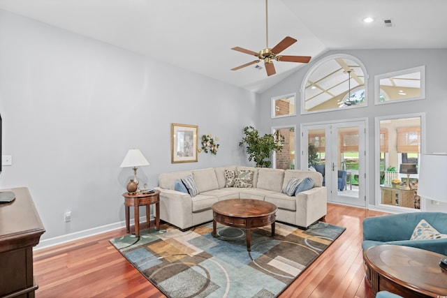 living room with high vaulted ceiling, french doors, ceiling fan, and light hardwood / wood-style flooring