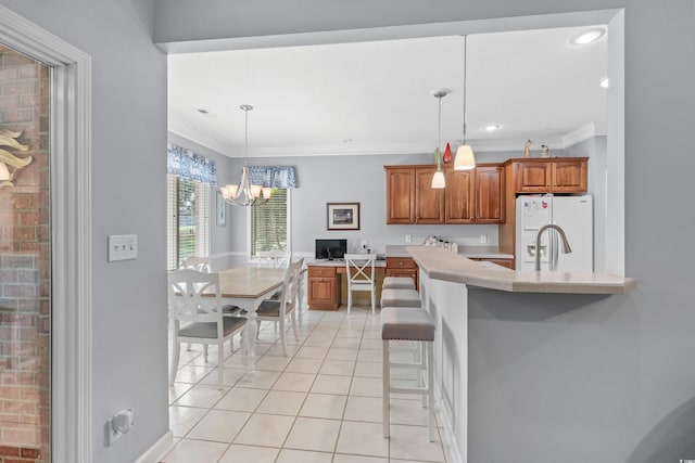 kitchen featuring a breakfast bar area, a notable chandelier, decorative light fixtures, and white fridge with ice dispenser