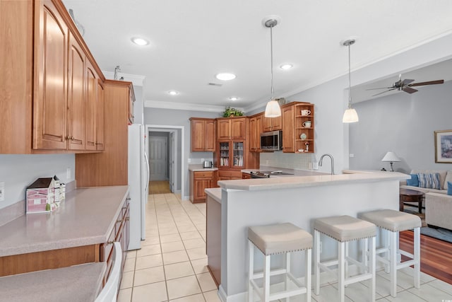 kitchen featuring crown molding, stainless steel appliances, kitchen peninsula, ceiling fan, and a breakfast bar area