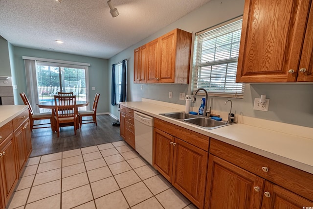 kitchen featuring a textured ceiling, dishwasher, sink, and light hardwood / wood-style flooring