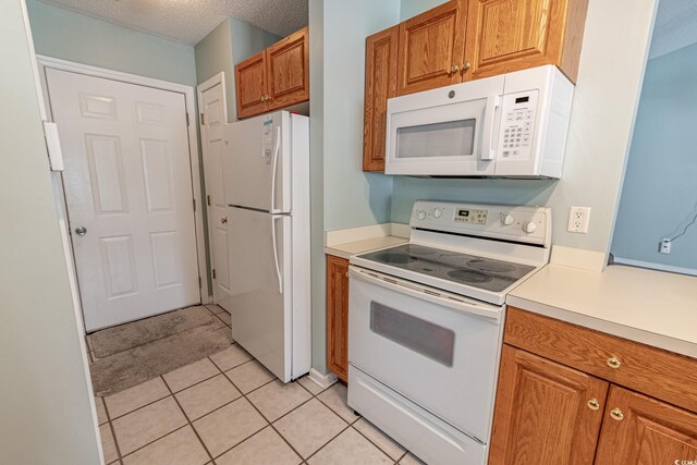 kitchen with white appliances, a textured ceiling, and light tile patterned flooring