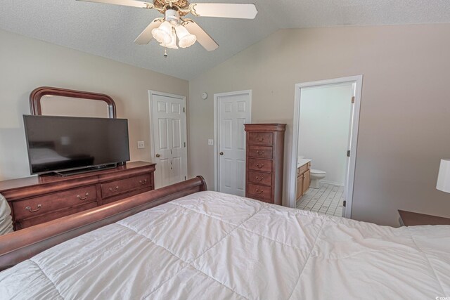 tiled bedroom featuring lofted ceiling, ceiling fan, ensuite bathroom, and a textured ceiling