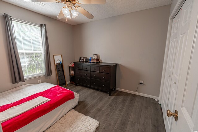 bedroom with dark wood-type flooring, a closet, ceiling fan, and a textured ceiling