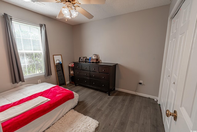 bedroom with wood finished floors, baseboards, ceiling fan, a closet, and a textured ceiling