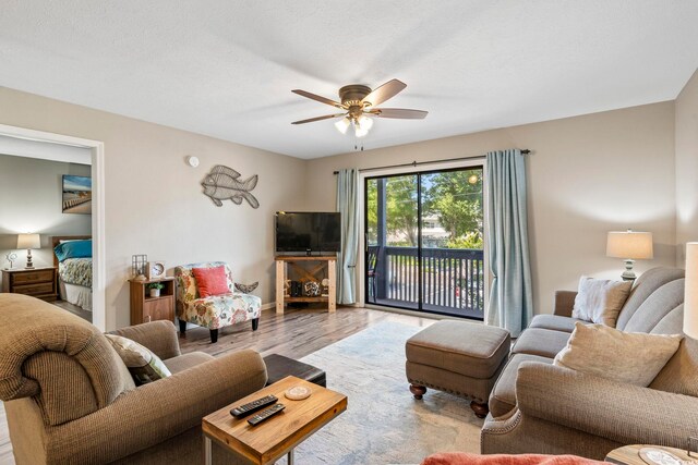 living room with a textured ceiling, wood-type flooring, and ceiling fan