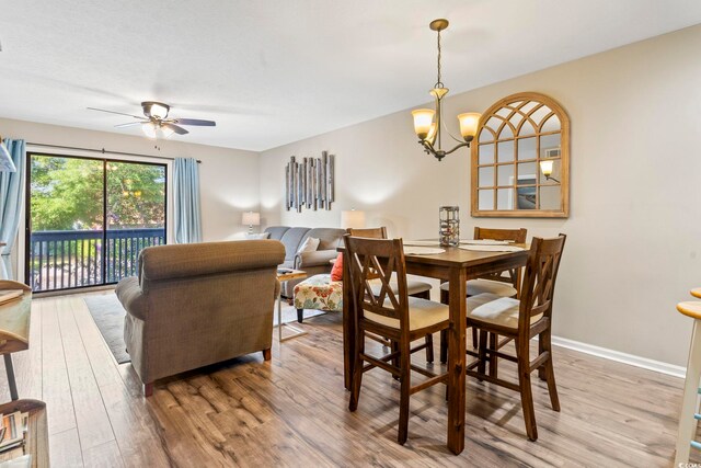 dining room featuring ceiling fan with notable chandelier and wood-type flooring