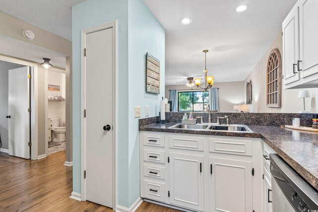 kitchen featuring hanging light fixtures, light hardwood / wood-style floors, white cabinetry, sink, and stainless steel dishwasher