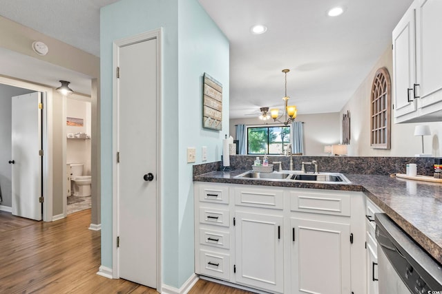 kitchen featuring dark countertops, stainless steel dishwasher, light wood-type flooring, and a sink