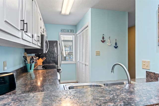 kitchen featuring a textured ceiling, stainless steel appliances, sink, and white cabinetry