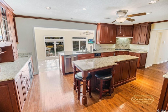 kitchen with a breakfast bar area, light hardwood / wood-style flooring, a kitchen island, and appliances with stainless steel finishes