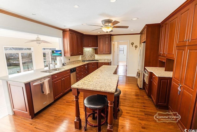 kitchen featuring a kitchen breakfast bar, stainless steel appliances, sink, hardwood / wood-style flooring, and a kitchen island