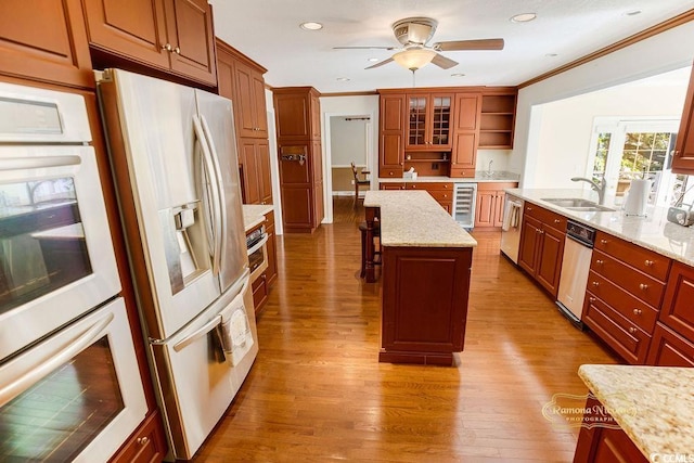 kitchen with stainless steel appliances, beverage cooler, sink, light hardwood / wood-style flooring, and a center island