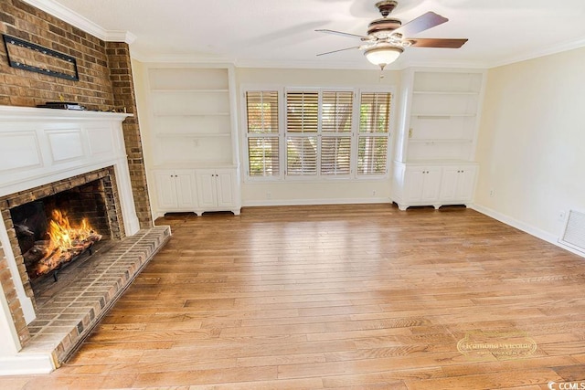 unfurnished living room featuring crown molding, a brick fireplace, light hardwood / wood-style flooring, built in shelves, and ceiling fan