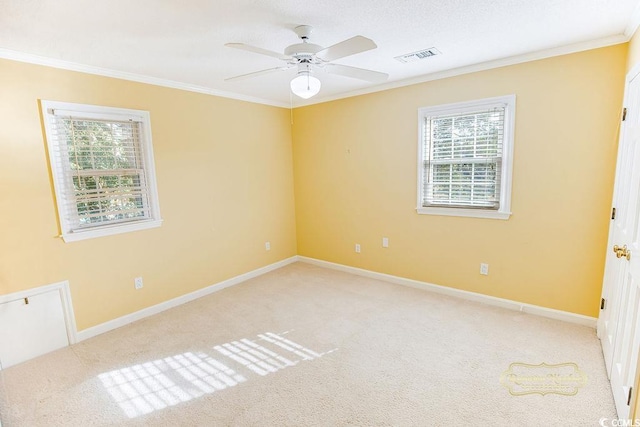 spare room with light colored carpet, a wealth of natural light, ornamental molding, and ceiling fan