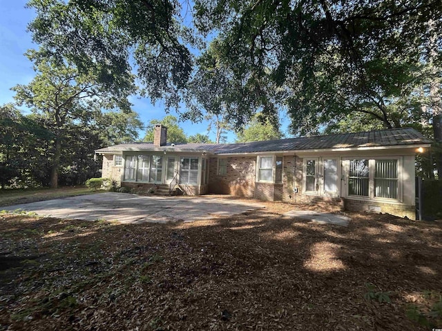 902 N 11th Ave N, North Myrtle Beach, SC 29582 - rear view of property with brick siding, a sunroom, a chimney, a patio, and metal roof