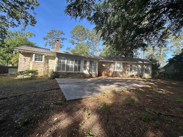 902 N 11th Ave N, North Myrtle Beach, SC 29582 - rear view of house with entry steps, a chimney, brick siding, a patio area, and metal roof