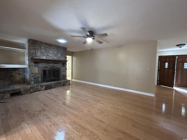 unfurnished living room featuring hardwood / wood-style flooring, ceiling fan, a fireplace, and a textured ceiling