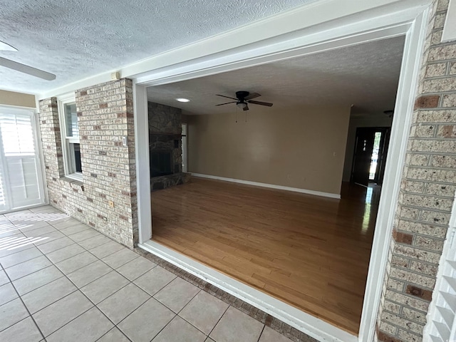 902 N 11th Ave N, North Myrtle Beach, SC 29582 - exterior space featuring ceiling fan, tile patterned flooring, a textured ceiling, brick wall, and a stone fireplace