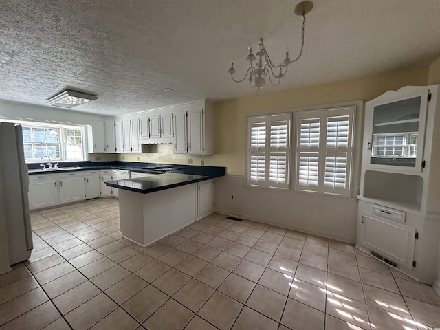 902 N 11th Ave N, North Myrtle Beach, SC 29582 - kitchen featuring freestanding refrigerator, a peninsula, dark countertops, white cabinetry, and light tile patterned floors