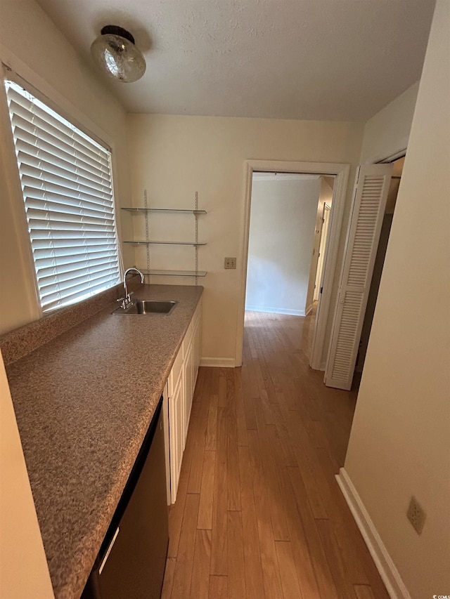 kitchen with dishwashing machine, sink, a textured ceiling, and light wood-type flooring