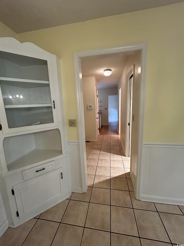 hall featuring built in features, a textured ceiling, and light tile patterned floors