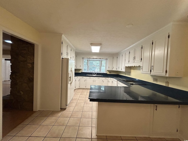 kitchen featuring sink, white fridge with ice dispenser, white cabinets, light tile patterned flooring, and kitchen peninsula