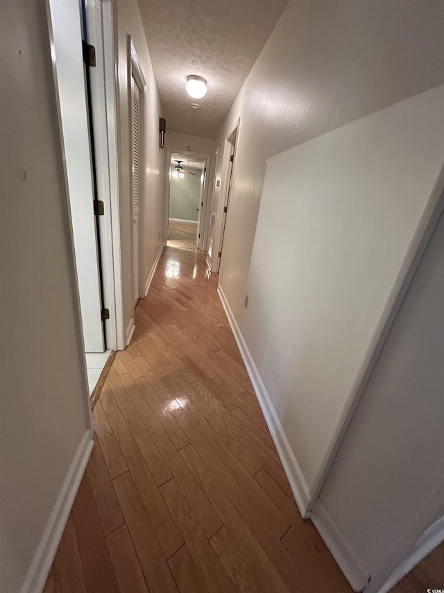 corridor featuring light hardwood / wood-style floors and a textured ceiling