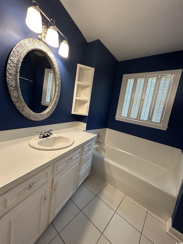 bathroom featuring tile patterned flooring, vanity, a tub, and a textured ceiling