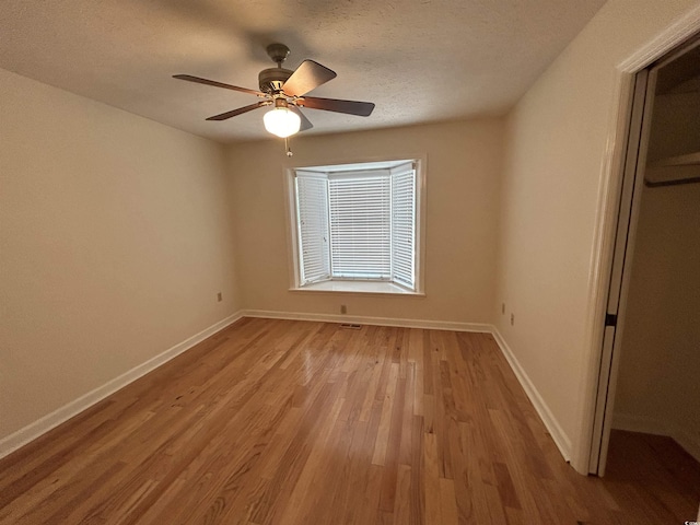 unfurnished bedroom with ceiling fan, a textured ceiling, and light wood-type flooring