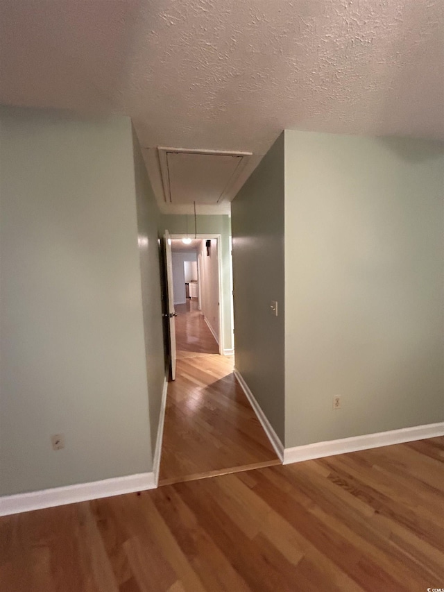 corridor with wood-type flooring and a textured ceiling