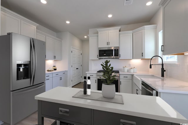 kitchen with sink, white cabinetry, tasteful backsplash, appliances with stainless steel finishes, and a kitchen island