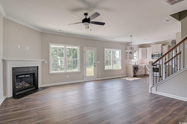 unfurnished living room with crown molding, a fireplace, ceiling fan with notable chandelier, and dark hardwood / wood-style floors