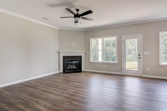 unfurnished living room with ceiling fan, dark wood-type flooring, ornamental molding, and a healthy amount of sunlight