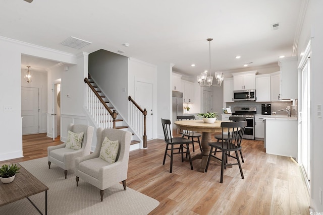 dining area with crown molding, sink, a notable chandelier, and light wood-type flooring