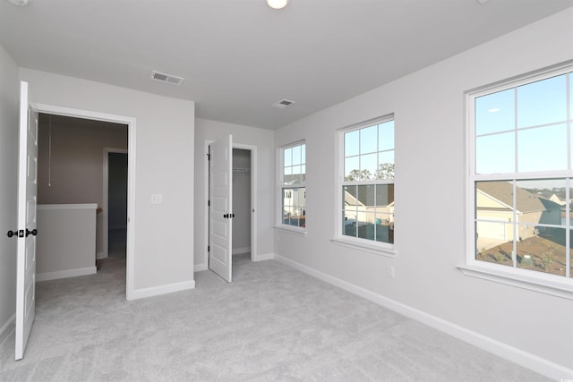 unfurnished bedroom with light colored carpet and a closet