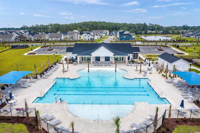 view of pool with a patio, a water view, and a lawn