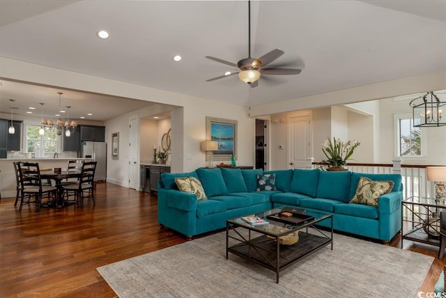 living room featuring ceiling fan with notable chandelier and dark wood-type flooring