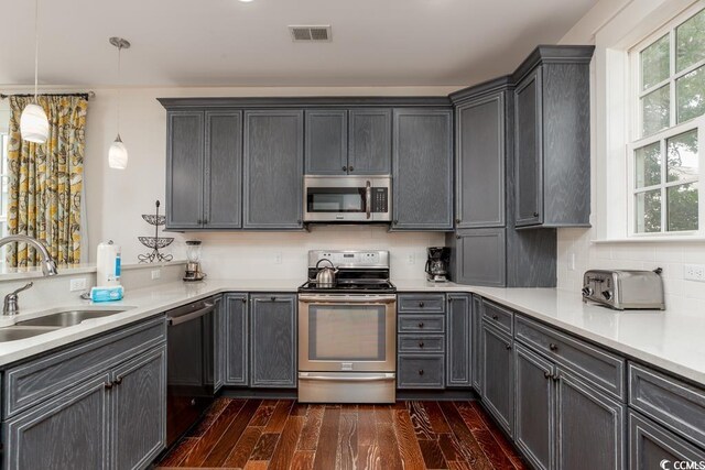 kitchen with stainless steel appliances, sink, dark hardwood / wood-style floors, pendant lighting, and tasteful backsplash