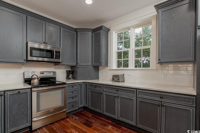 kitchen with dark wood-style floors, stainless steel appliances, backsplash, and light countertops