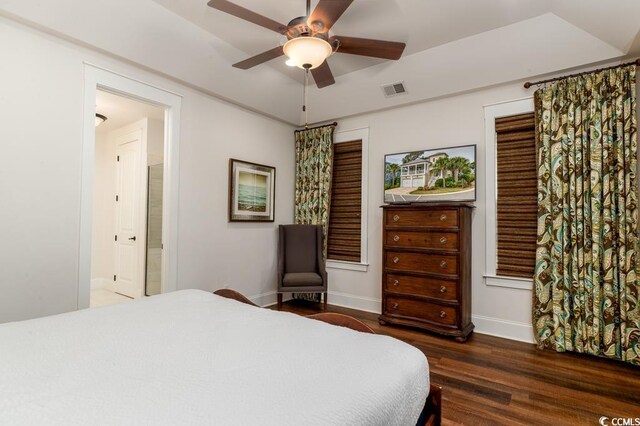 bedroom with dark wood-type flooring, ceiling fan, and ensuite bath